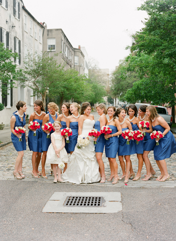 group portrait, bride with bridesmaids in blue above the knee dresses, red bouquets, urban street - photo by South Carolina based destination wedding photographer Virgil Bunao